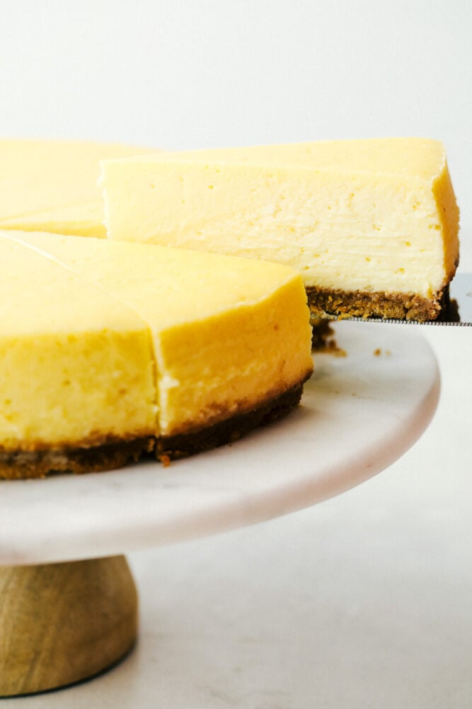 New York Cheesecake is a smooth, creamy dessert that is decant and always a favorite! This is an easy cheesecake that anyone can make. A slice of New York cheesecake being served.