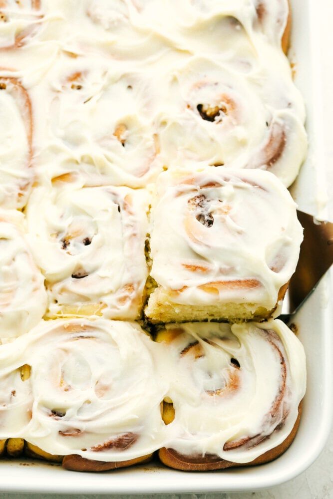 Overnight Cinnamon Rolls is a recipe you need in your arsenal. They make waking up worth it in the morning! Scooping out a cinnamon roll.