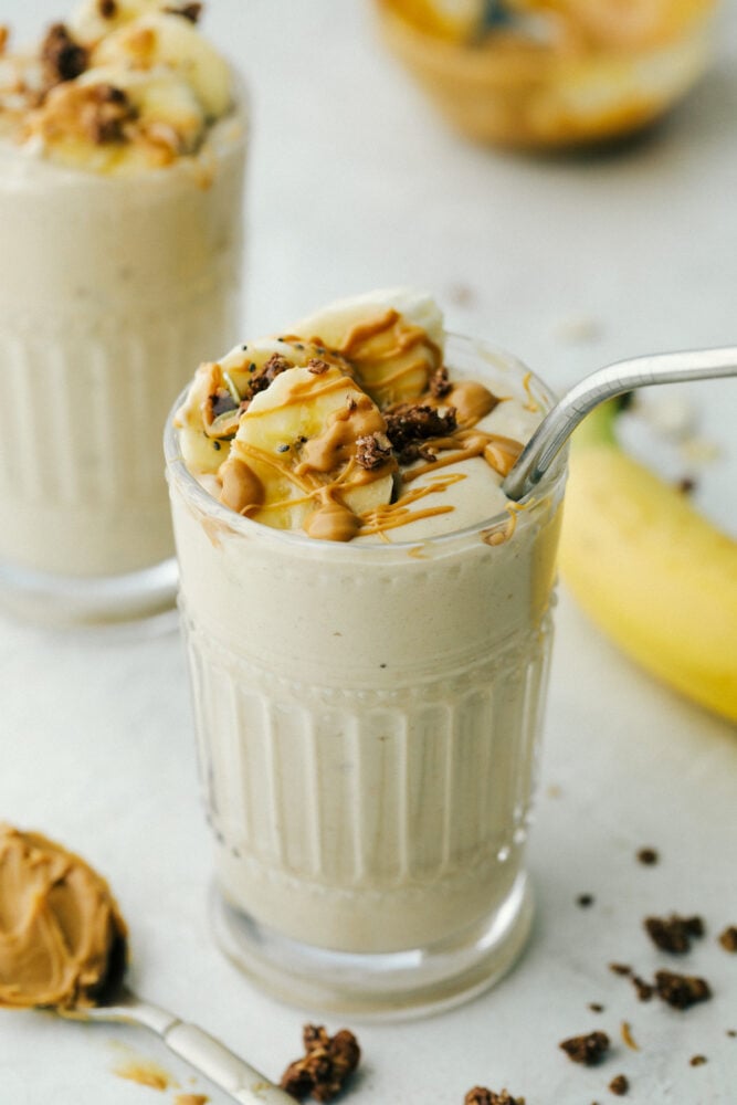 Peanut Butter Banana Smoothie is a rich refreshing drink that is good for you too! Full of protein, vitamins, and minerals use it as a workout recovery drink or a snack. A Banana smoothie with a metal straw in a glass cup.