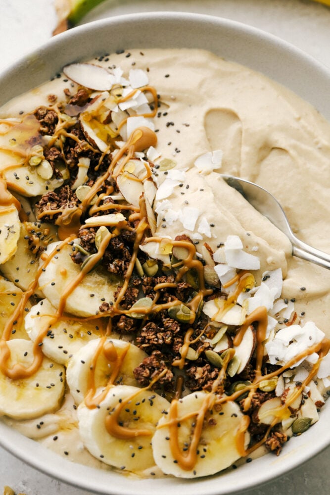 Peanut Butter Smoothie Bowl is one of the best ways to get your protein in for the day! It tastes like you are eating luscious ice cream, only it's so much better for you Scooping a bite of peanut butter smoothie with a spoon.