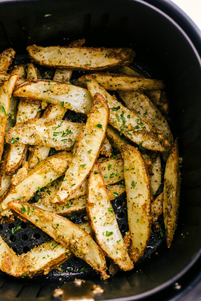 Air Fryer Potato Wedges are seasoned with a crispy outside and perfectly tender on the inside! These are so insanely delicious you are going to love them! Cooked potato wedges in the air fryer ready to eat.
