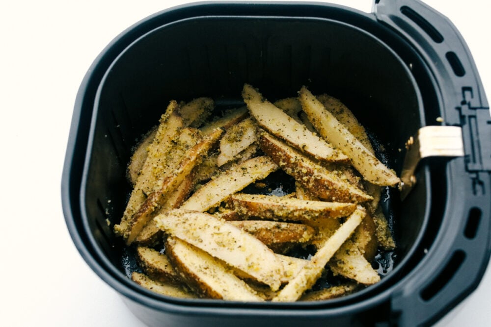 Air Fryer Potato Wedges are seasoned with a crispy outside and perfectly tender on the inside! These are so insanely delicious you are going to love them! Air fryer basket full of wedges ready to cook.