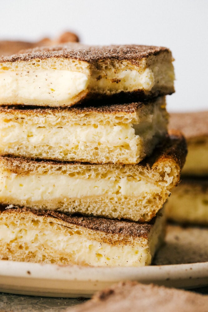 Churro cheesecake bars stacked with a bite out of them.