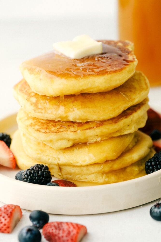 I am not joking when I say these are to die for Cornbread pancakes with honey butter syrup. These may well be the most amazing pancakes you will ever have! A stack of cornmeal pancakes dripping in honey butter syrup.