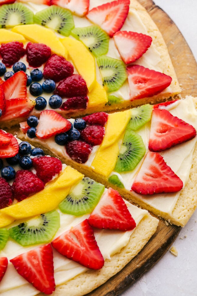 This Fruit Pizza is a sweet refreshing dessert that is always a hit! Full of color, and pizzaz this is a delicious way to eat your fruit! Taking a slice of fruit pizza.