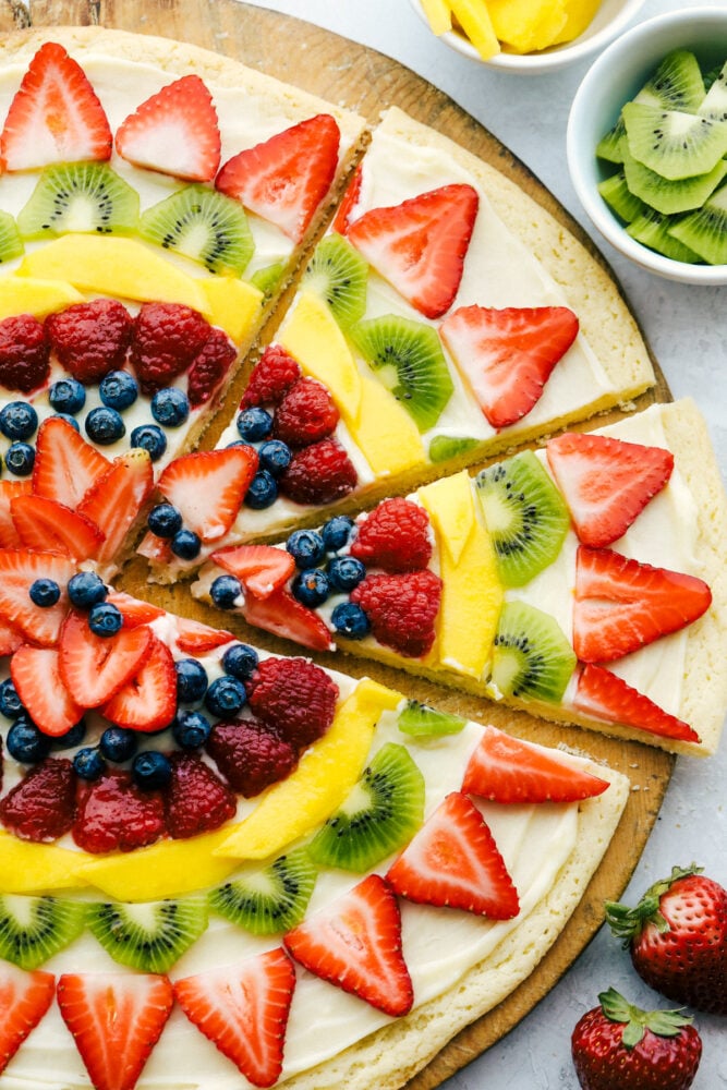 This Fruit Pizza is a sweet refreshing dessert that is always a hit! Full of color, and pizzaz this is a delicious way to eat your fruit! Fruit pizza cut into slices.