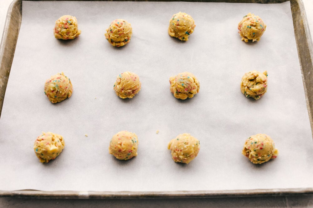 Funfetti Cheesecake Pudding cookies are some of the best tasting and best looking cookies you'll ever have! Made with pudding mix, these are soft, chewy and oh so delicious! Formed cookie dough balls on a parchment lined cookie sheet.