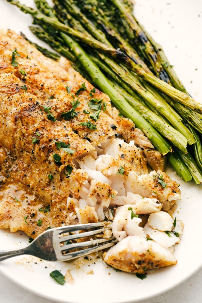 This Grilled Cajun Garlic Butter Cod is the only recipe you will need this summer! The cod is tender and juicy and the flavor is spicy and buttery, it's insanely delicious! Taking a bite of the cod with a fork.