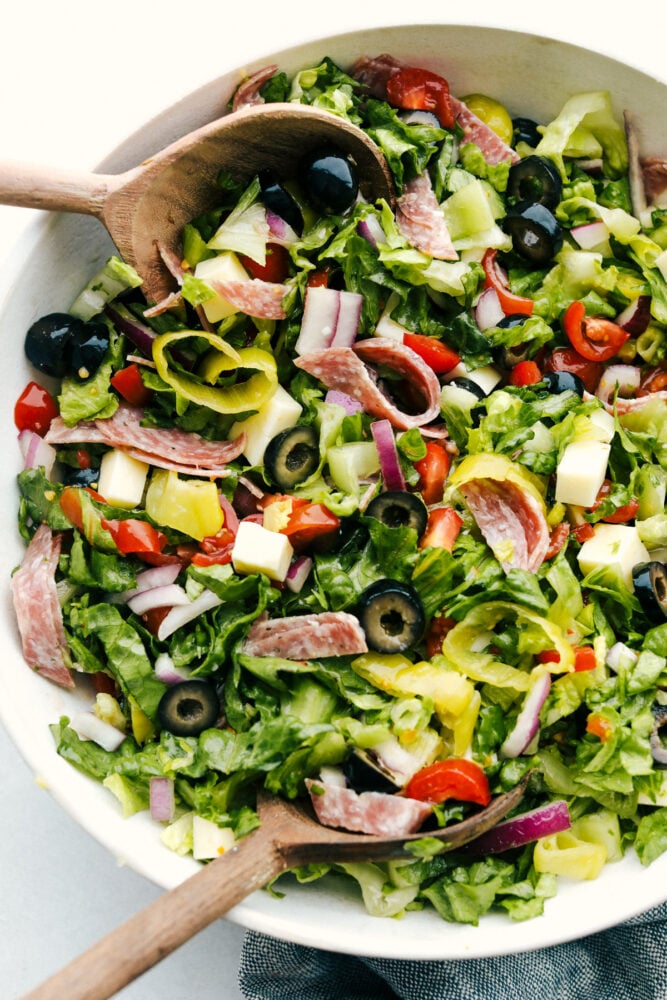 Italian Chopped Salad is stuffed with flavor and texture that is highly satisfying. Full of classic Italian flavors, this salad is going to be a huge hit at your next gathering! A bowl of Italian chopped salad with serving spoons