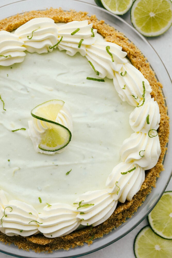 No Bake Key Lime PIe is a slice of tropical heaven. This has a sweet crunchy crust filled with a refreshing, creamy and zippy lime filling perfect for the summer heat! No-bake key lime pie with lime zest decorating the top.