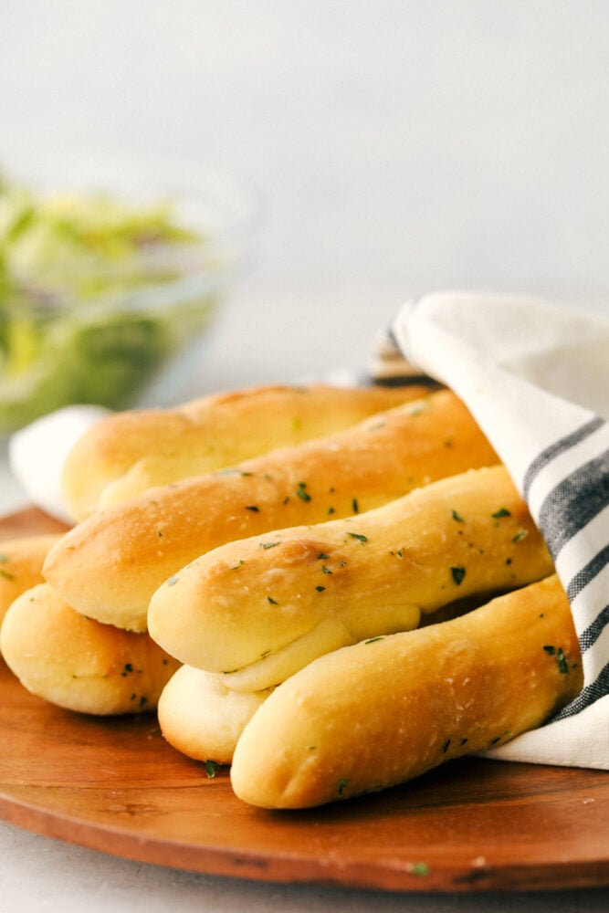 These copycat Olive Garden Breadsticks are insanely delicious! Fresh, buttery, and garlicky you can still have unlimited breadsticks, only these taste better! A bunch of breadsticks wrapped in a towel ready to eat.