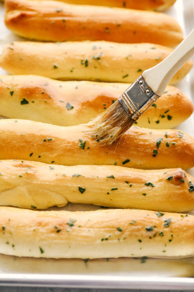 These copycat Olive Garden Breadsticks are insanely delicious! Fresh, buttery, and garlicky you can still have unlimited breadsticks, only these taste better! Brushing on more buttery seasoning after they have baked.