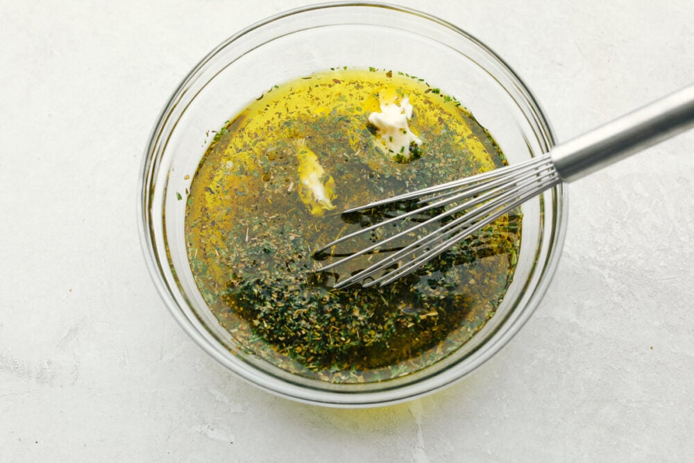 Olive Garden Salad Dressing is one of the best things at the restaurant, and now you can make it at home! Instead of having to go to the restaurant, you can have this tasty dressing anytime you crave it in the comfort of your own home! Mixing all the ingredients in a glass bowl with a whisk.