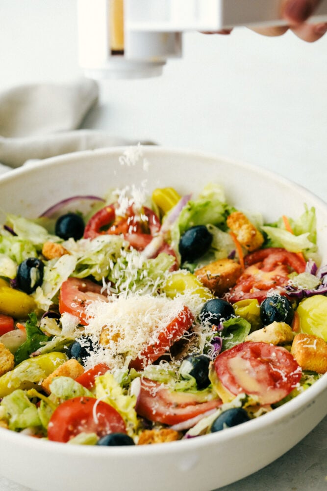 Copycat Olive Garden Salad is one of my all-time favorite restaurant salads, and now you can make it right at home. Itโs bright, zesty, and packed with that fresh, irresistible flavor everyone loves. Adding Cheese to a bowl of copycat Olive Garden salad.