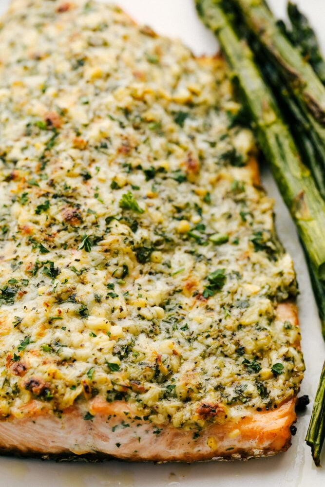 Salmon that is baked in foil and brushed in a Parmesan Garlic Herb Marinade. It seals in the amazing flavor and cooks the salmon to tender and flaky perfection! Salmon with parmesan and garlic on a platter.