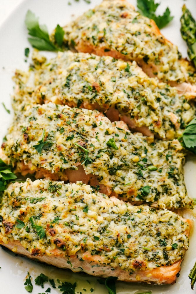 Salmon that is baked in foil and brushed in a Parmesan Garlic Herb Marinade. It seals in the amazing flavor and cooks the salmon to tender and flaky perfection! Portioned out salmon with parmesan garlic and butter topping.