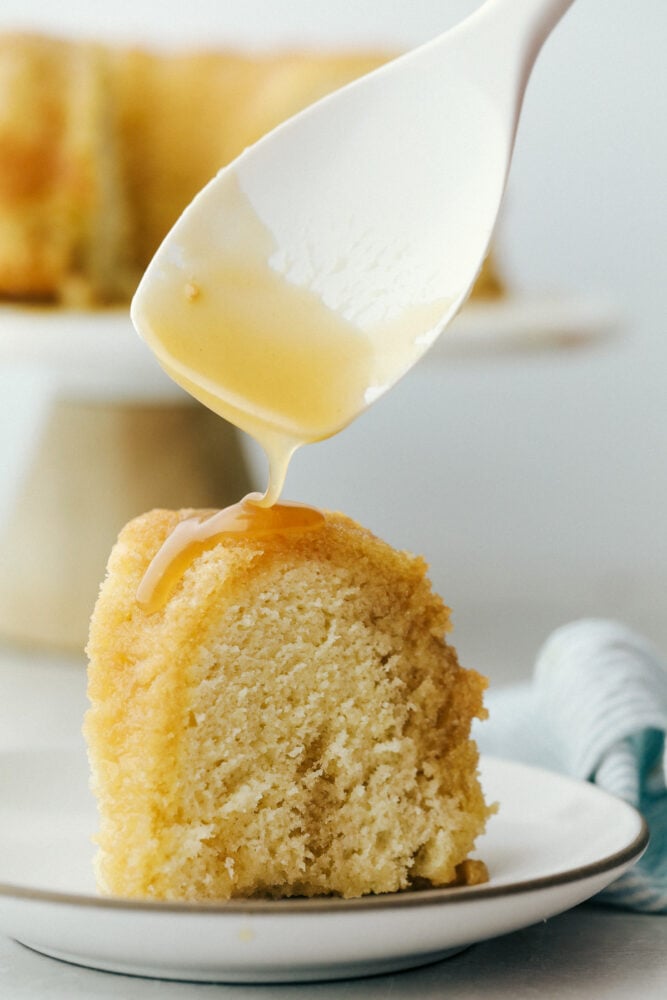 Rum Cake is a rich dense cake that is overflowing with butter rum flavor that is insanely delicious. This cake is moist and the rum syrup adds a layer of decadence that is next level amazing! The sauce being spooned over a piece of rum cake.