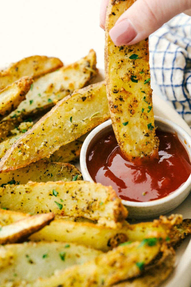 Air Fryer Potato Wedges are seasoned with a crispy outside and perfectly tender on the inside! These are so insanely delicious you are going to love them! Dipping a potato wedge in some ketchup.