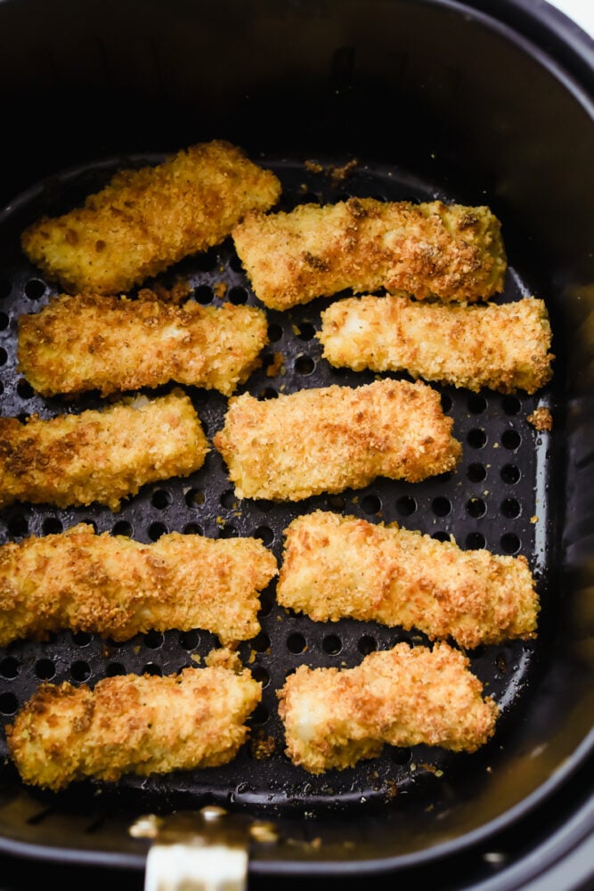These air fryer fish sticks are going to rock your family's world. Never again will you make fish sticks from a box, these are insanely delicious! Cooked fish sticks in the basket of the air fryer.