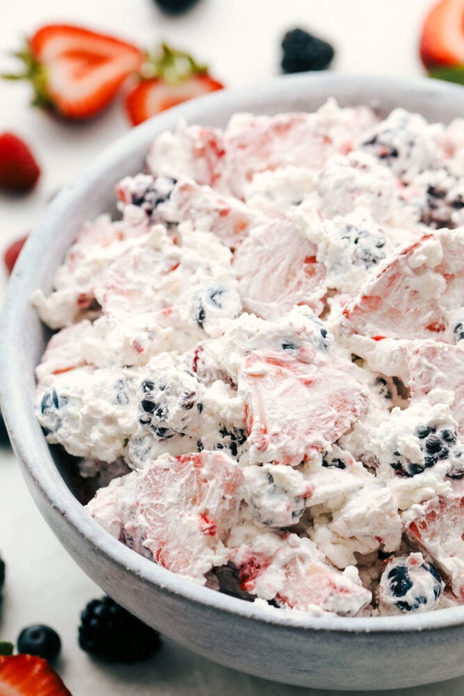 Berryย Cheesecake Salad has only the freshest berries combined with a creamy cheesecake fluff. ย This is so amazingย and will be the hit of any gathering! Berry cheesecake salad in a white bowl.
