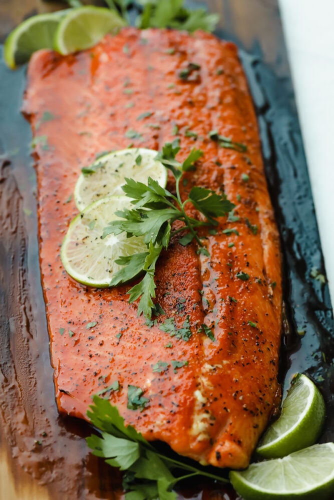 Smoky, woodsy flavors meet summery honey and lime in this melt-in-your-mouth salmon recipe! You are not going to be able to get enough of this irresistible Cedar Plank Honey Lime Salmon! Grilled salmon on cedar plank with lime garnish.