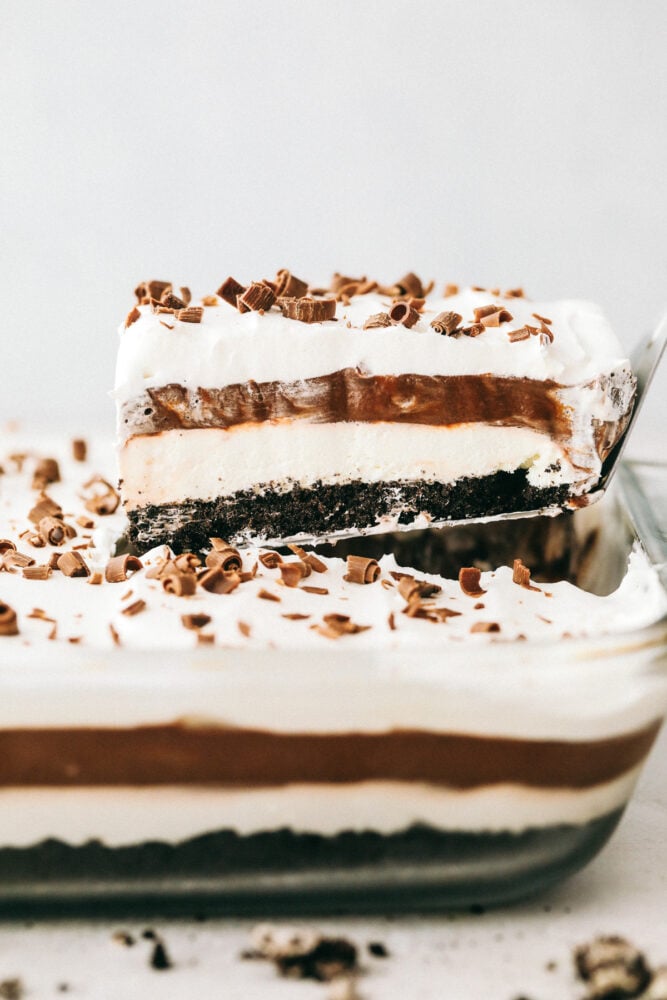 Oreo Lasagna is a no-bake slice of chocolate heaven! Layered with a cream cheese and pudding layer, sandwiched between whipped topping and luscious Oreo crust, it's too die for! Scooping out the chocolate lasagna from a 9x13.