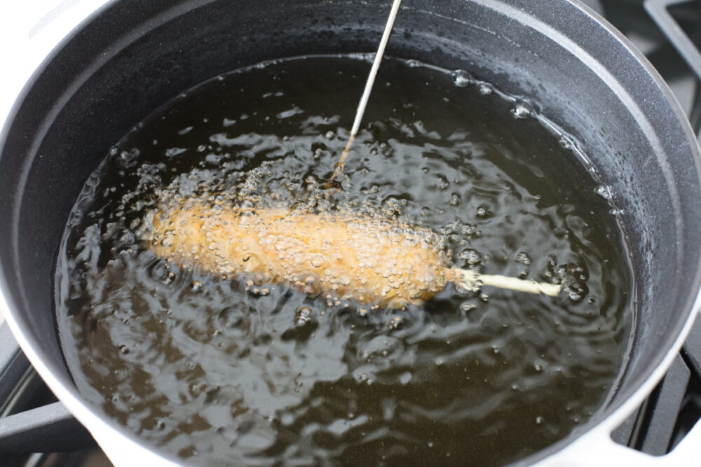 Homemade corn dogs are crispy golden on the outside and perfectly cooked on the inside. These are super easy to make at home and the whole family is going to love how they taste! Frying the corn dogs.
