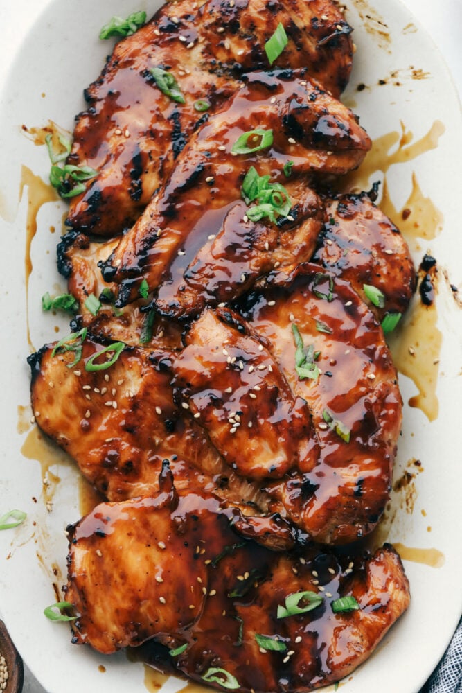 Grilled Teriyaki Chicken is the ultimate quick and easy, absolutely delicious dinner! Tender juicy chicken is soaked in the BEST Teriyaki Sauce then grilled to perfection Grilled chicken with teriyaki sauce on a white plate.