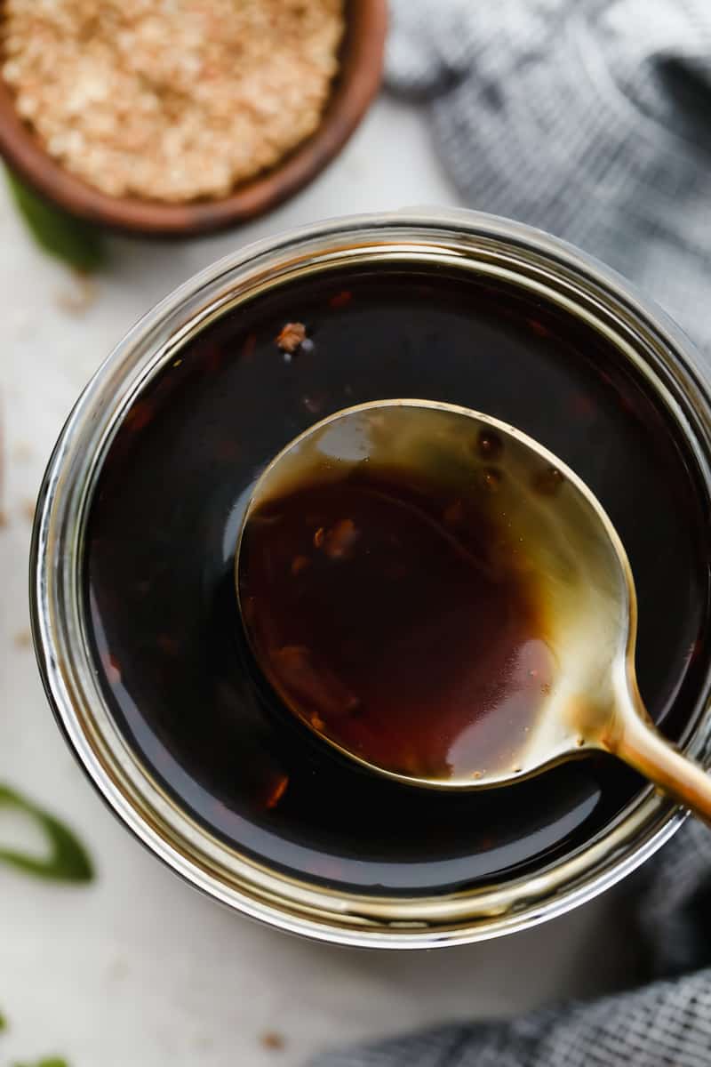Teriyaki Sauce is super easy, takes only 10 minutes to make and is way better than store-bought! Made with simple ingredients, this is going to become a staple for your kitchen. Scooping out a spoonful of teriyaki sauce from the jar.
