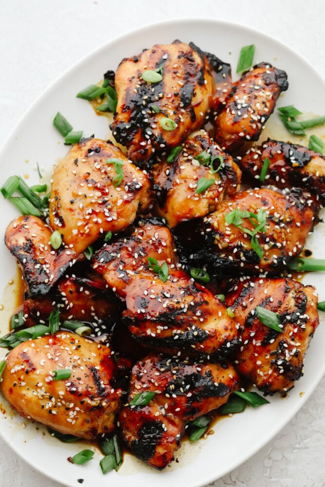 This Grilled Honey Garlic Chicken is healthy and delicious with a sweet, sticky garlic glaze. It only takes 5 ingredients to make the marinade and cooks up in less than 10 minutes. Grilled Honey Garlic Chicken on serving dish with green onion garnish.