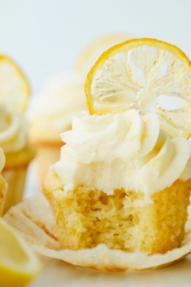 The AMAZING sweet and zesty flavors of these Lemon Cupcakes will have you hooked! Fresh lemon adds a pinch of summer to a classic, decadent treat. Lemon cupcake with a bite taken out of it