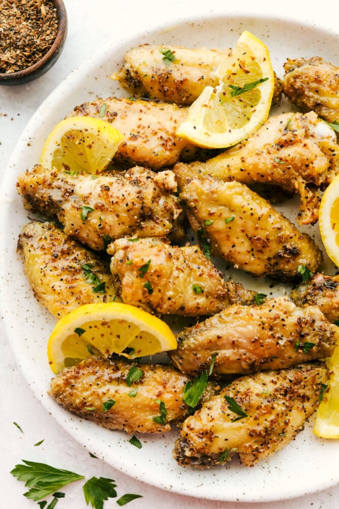Lemon Pepper Chicken Wings are buttery, zesty, and will WOW at your next family get-together! They are super easy to make and pack delicious flavor in every juicy bite! Lemon Pepper Wings with lemon garnish on plate.