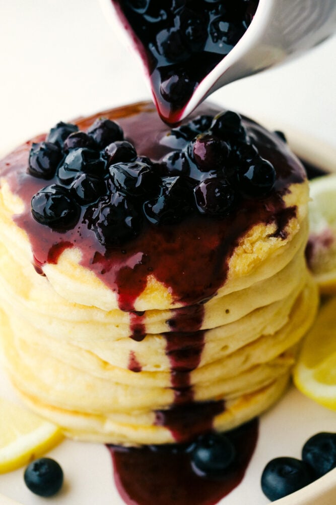 Lemon Ricotta Pancakes are fluffy, tender pancakes that are elevated to a whole new level. The ricotta adds protein and a lightness that is absolutely divine while the lemon gives it a bit of a tangy taste that you are going to love! Blueberry sauce drips down a stack of ricotta pancakes.