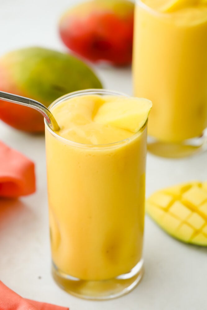 Mango Smoothie is a cool refreshing summertime treat you are going to love! Sweetened with banana and honey, this is summer in a glass Mango smoothie in a glass with a straw.