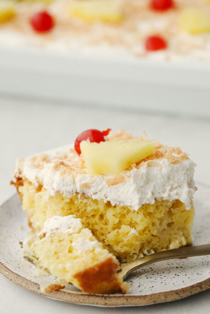 Pina Colada Poke Cake is a little slice of tropical paradise on a plate! Rich in flavor this is a light fluffy cake everyone is going to love! A slice of pina colada poke cake.