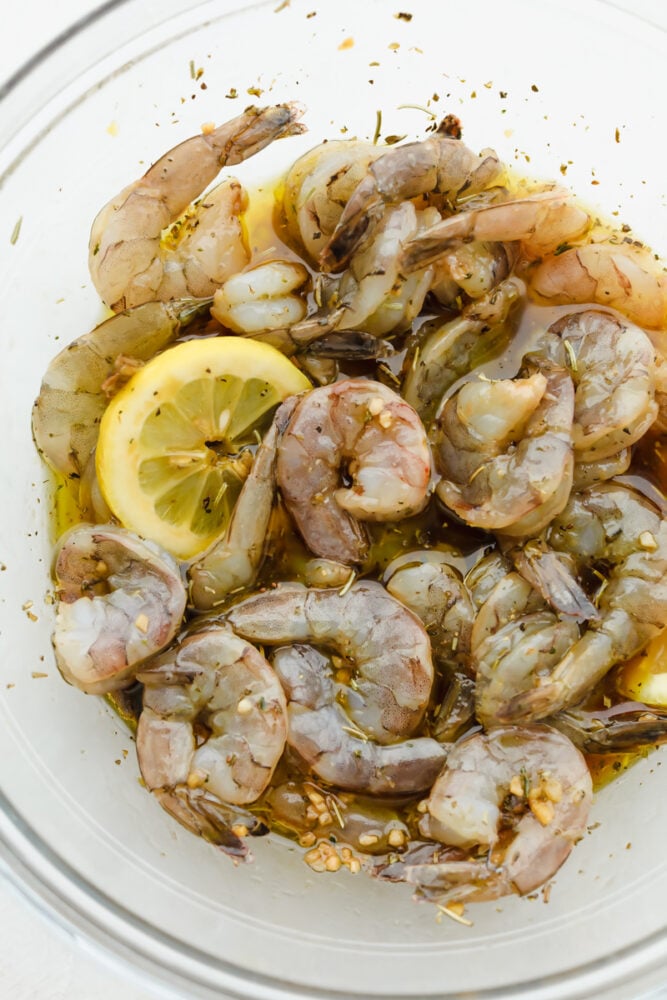 Layer this amazing marinade onto your shrimp for a perfectly rich, savory flavor with a pop of lemon your taste buds will LOVE! The drool-worthy flavor combinations and ease of preparation make this Shrimp Marinade a recipe to come back to over and over again. Fresh shrimp in marinade with lemon slices.