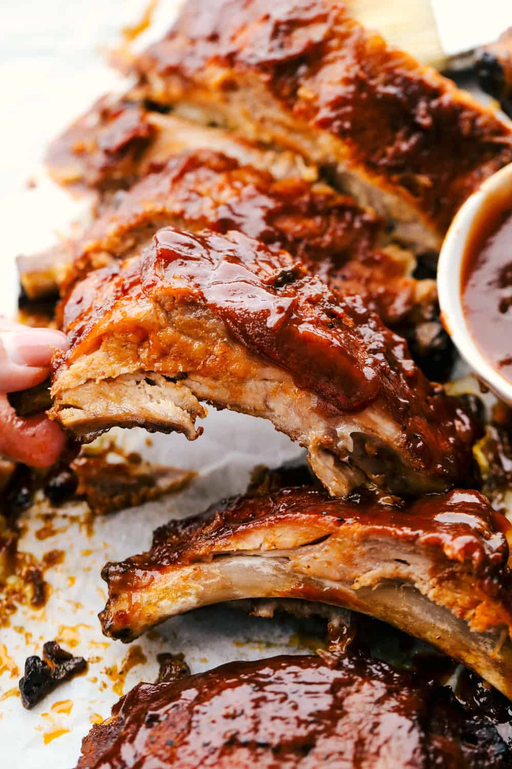 Myย Slow Cooker Ribsย are hands-down one of my favorite recipes on the site! They fall off the bone, are coated in sticky-sweet sauce, and are unbelievably easy to make. Close up of the slow cooker ribs.