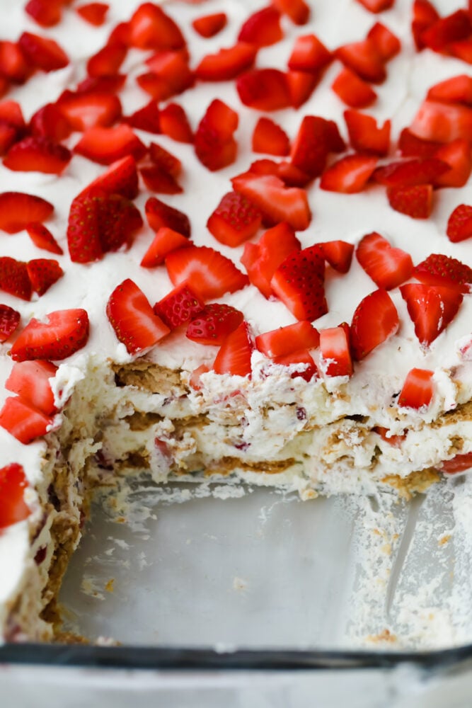 Strawberry Icebox Cake is the cool, creamy, and moist no-bake dessert of your dreams. Add a pop of juicy strawberry and you will never want to make cake another way! Strawberry icebox cake with piece cut out.