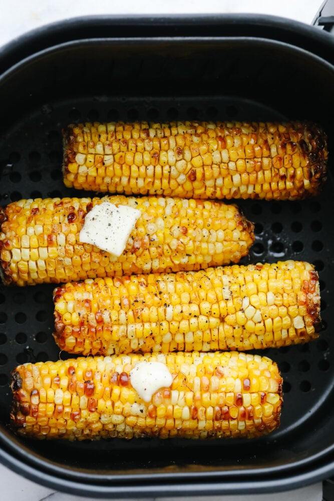 Air Fryer Corn on the Cob is going to change the way you cook corn. Super fast, tender, and full of flavor air fryer corn is insanely delicious. Air Fryer corn on the cob in the basket with butter.