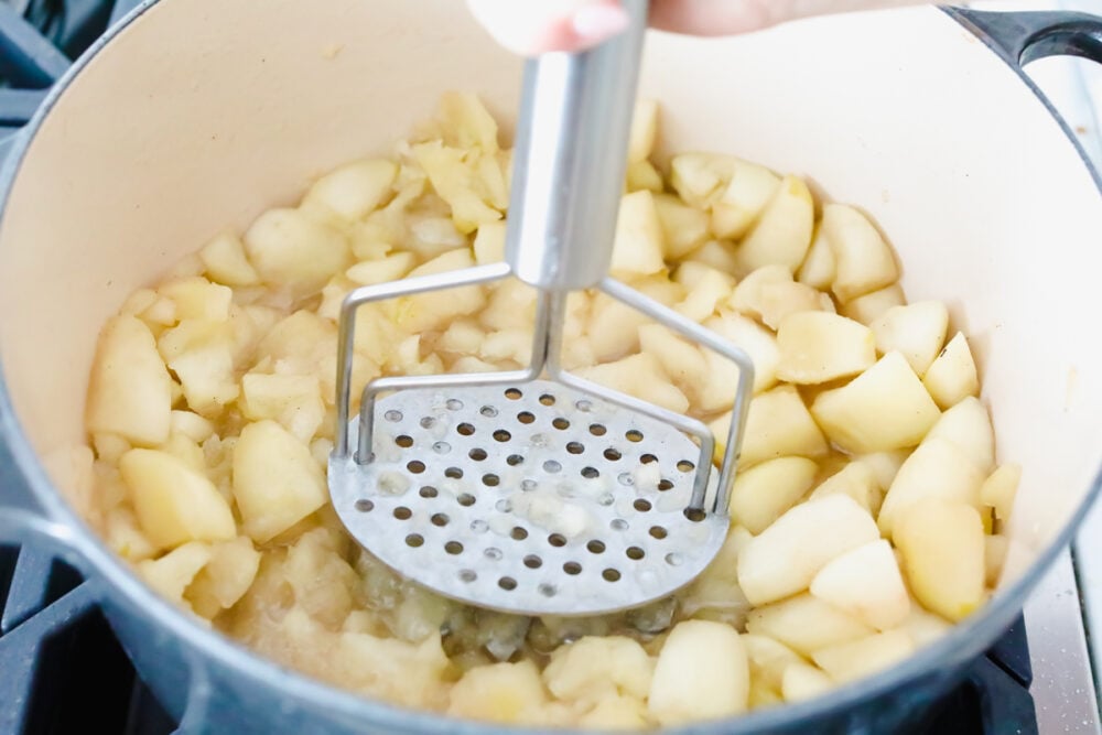 I love homemade applesauce! It is such a simple way to incorporate all of the apples that I have in my fridge! PLUS as a bonus, my kids are more inclined to eat something so simple! Cooked apples being mashed up.
