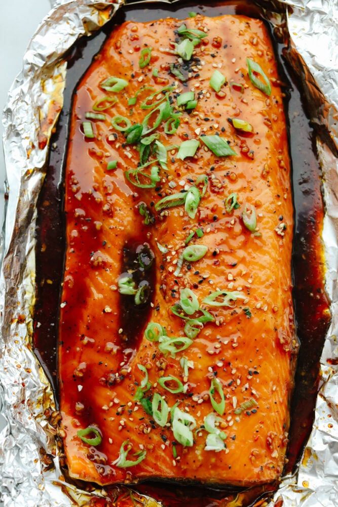 Blanketed with an insanely good soy garlic glaze, this juicy Asian glazed salmon is to die for! With how healthy and delicious it is, it will become your new lunch go-to! Salmon in tin foil covered in glaze.