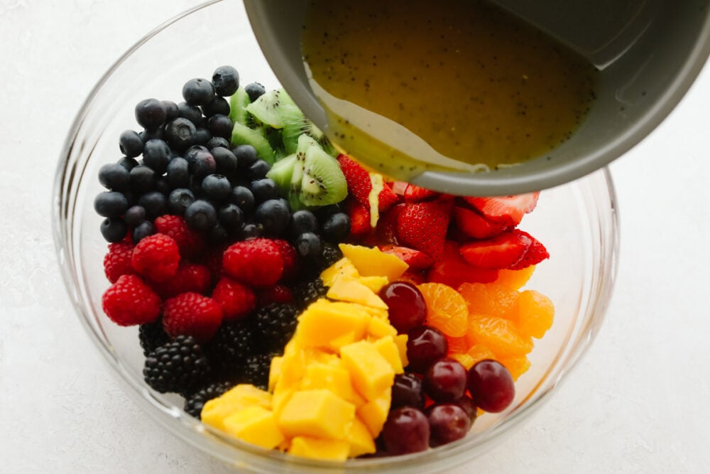 Blackberry Lime Fruit Salad showcases tons of fresh, summer fruit and has a delicious easy dressing. Refreshing, light, and sweet, this fruit salad will be eaten in no time! Pouring lime dressing over fruits.