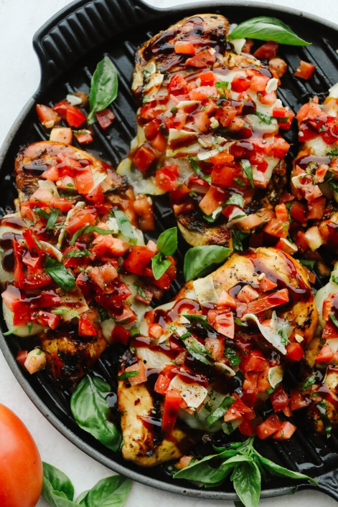 Bruschetta Chicken is a delicious, low-carb meal that packs big, mouthwatering flavor. With fresh vegetables, garlic, a sticky-sweet balsamic glaze, and homemade Italian Seasoning, this will be your new go-to lunch. Pieces of Bruschetta Chicken on skillet.