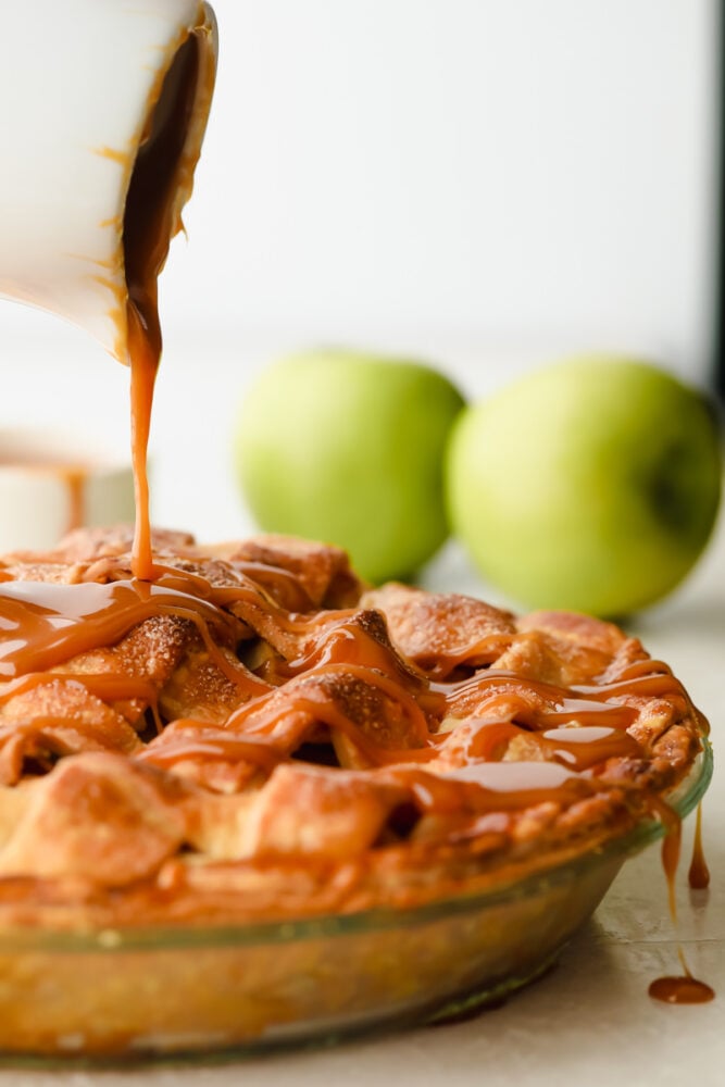 Caramel Apple Pie is the traditional American dessert, but totally elevated. Sour tart apples are smothered in caramel, it's insanely delicious. Pouring the caramel over the apple pie.