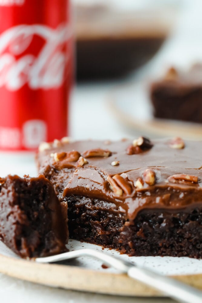 Coca Cola cake is an easy-to-make chocolate cake, topped with pecans and ooey-gooey chocolate frosting. It is so easy and absolutely delicious, you are going to love this cake and its subtle soda flavor! Taking a bite of Coca-Cola cake.