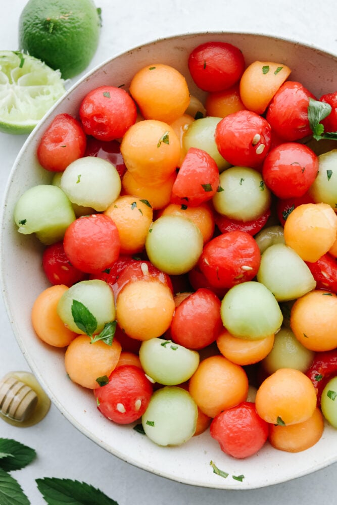 I don't know about you but nothing hits the spot more on a hot summer day than fresh fruit and salads! Combine the two together and our melon salad will leave you feeling refreshed and satisfied! A bowl filled with different types of melons topped with a dressing.