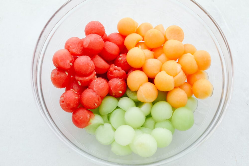 I don't know about you but nothing hits the spot more on a hot summer day than fresh fruit and salads! Combine the two together and our melon salad will leave you feeling refreshed and satisfied! A bowl filled with fruit, all scooped as small pieces.