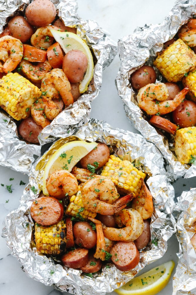 Shrimp Boil Foil Packets bring you juicy, tender shrimp and veggies tossed in Cajun spices! These pack all the kick and amazing flavor of Cajun cooking without the mess! Shrimp Boil Foil Packets with lemon garnish.