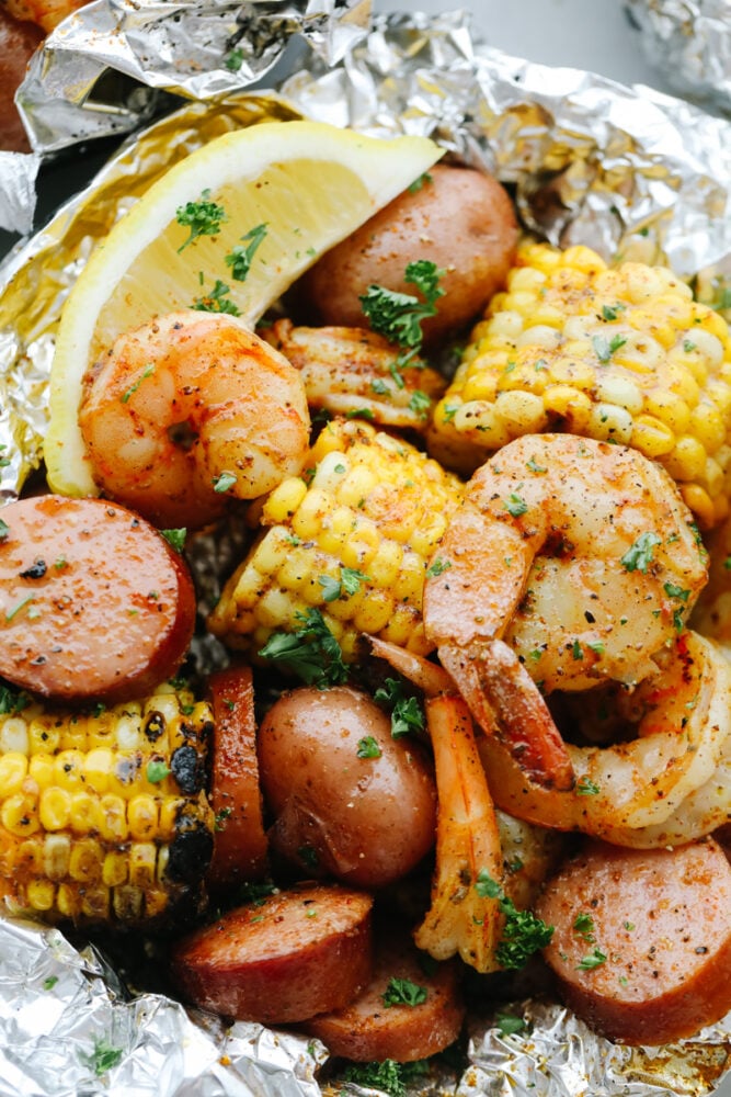 Shrimp Boil Foil Packets bring you juicy, tender shrimp and veggies tossed in Cajun spices! These pack all the kick and amazing flavor of Cajun cooking without the mess! Close-up of Shrimp Boil Foil Packet with lemon garnish.