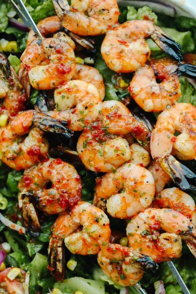 This easy grilled shrimp salad recipe is the perfect solution to your summer dinner needs! Itโs healthy, quick, and full of grilled chipotle flavor. Grilled shrimp on skewers coated in chipotle sauce.
